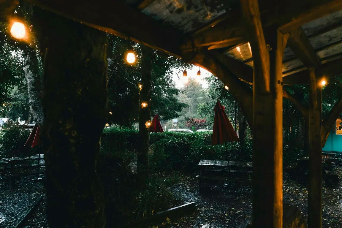 雨の日に屋根の下で明かりの灯る席
