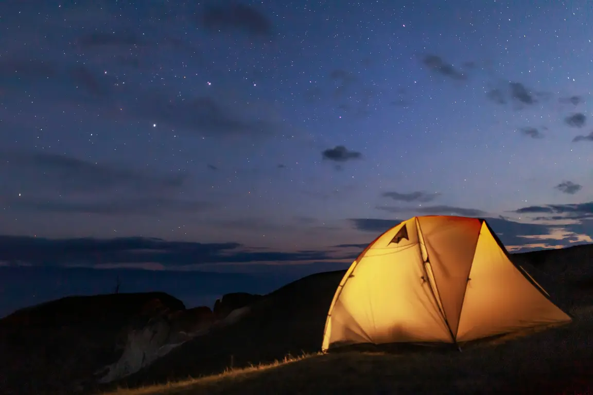 夜の山で明かりの灯るドーム型テント