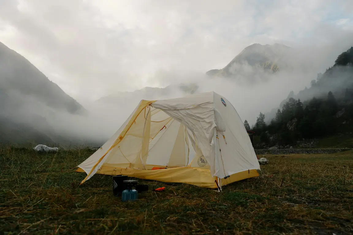霧のかかる山の草地に張られたテント